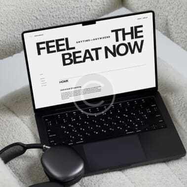 Laptop screen displaying "Feel the Beat Now" website with wireless earbuds