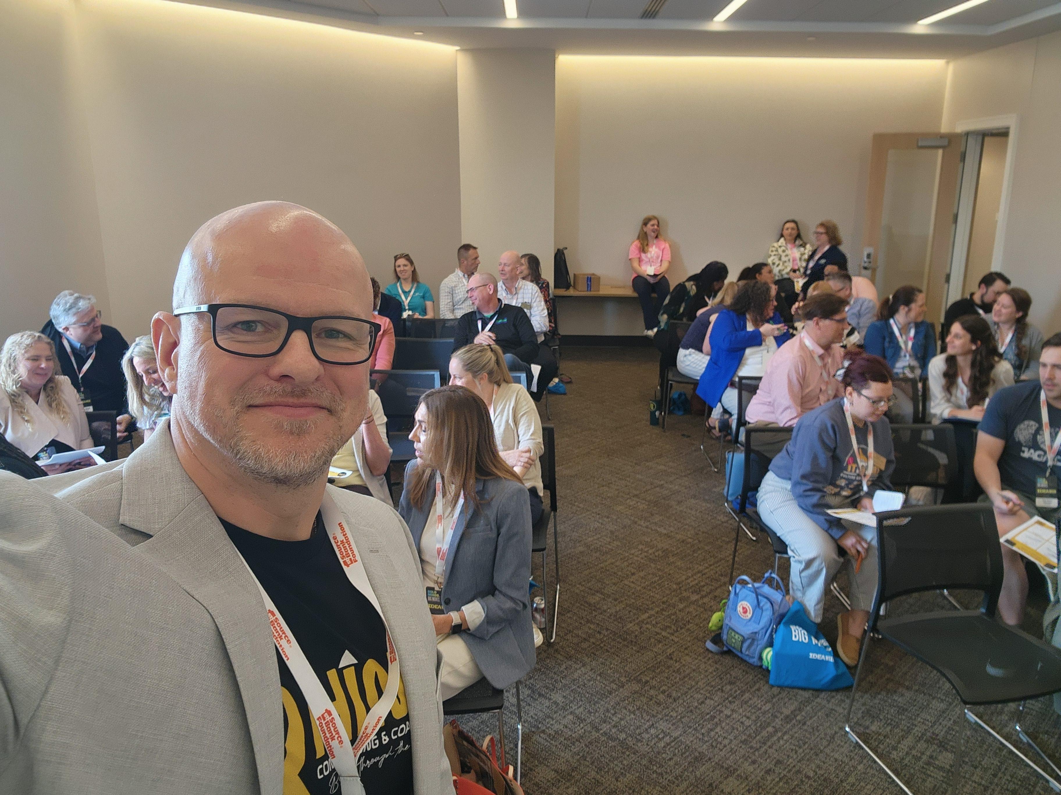Ryan Woodruff taking a selfie with workshop attendees seated in a training room