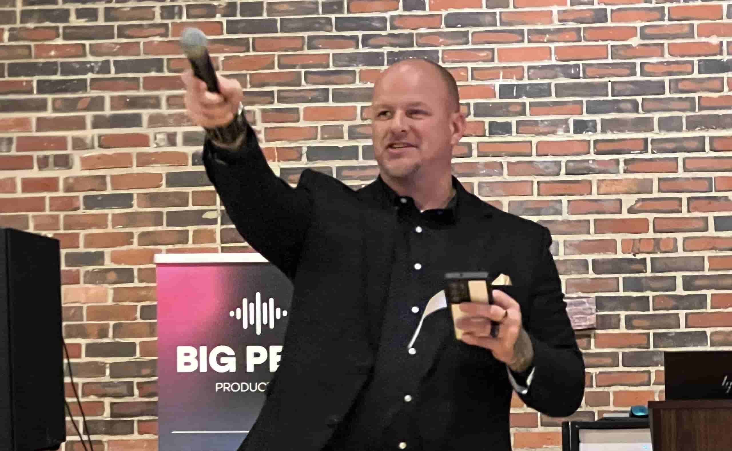 Man speaking on stage with microphone at event