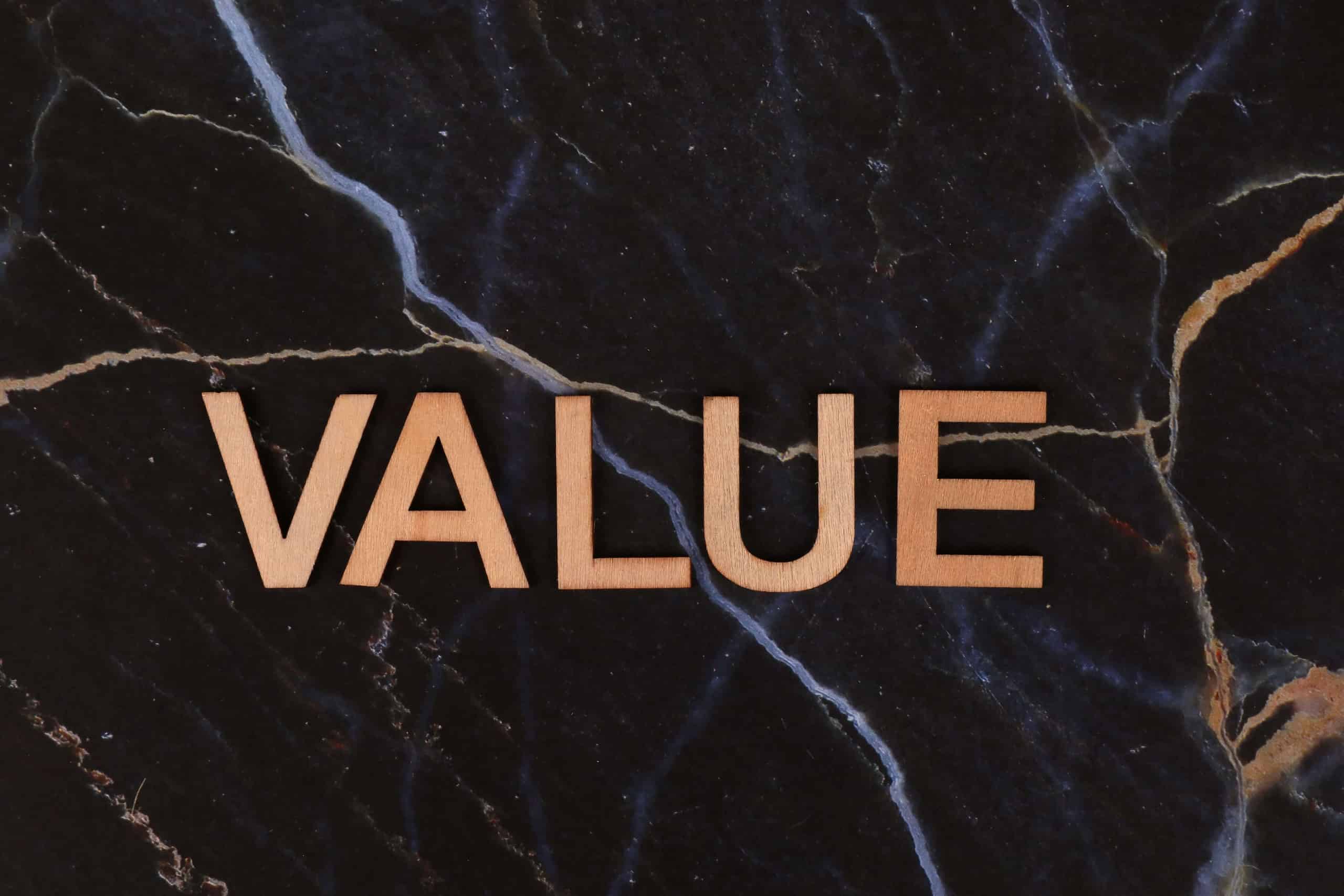 Wooden letters spelling "VALUE" on a black marble surface
