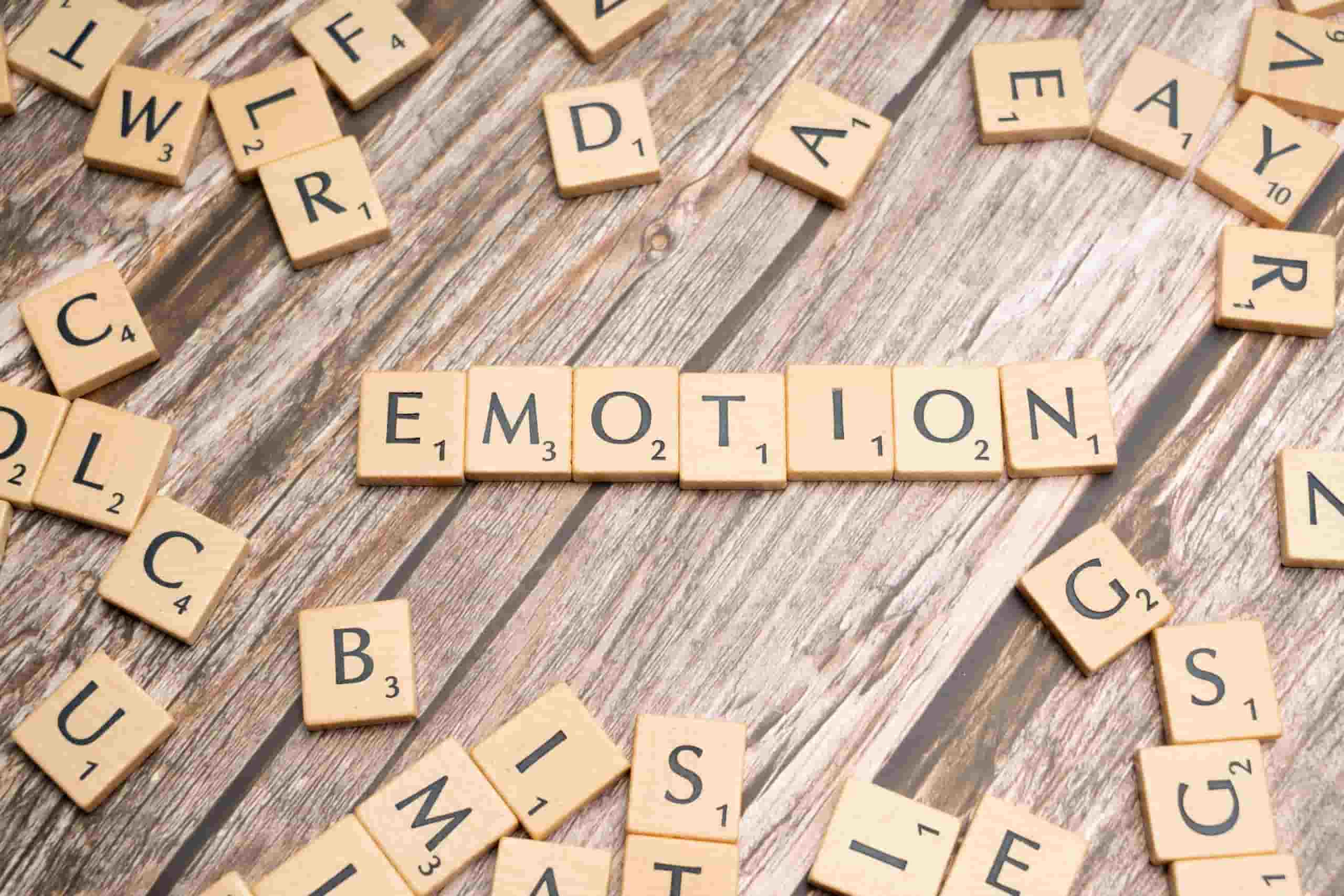Scrabble tiles spelling "EMOTION" on a wooden table